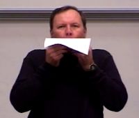 Person blows across top of a piece of paper