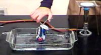 Open, empty soda can placed upside down in tray of water