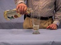 Pouring cooking oil into a beaker containing a Pyrex rod
